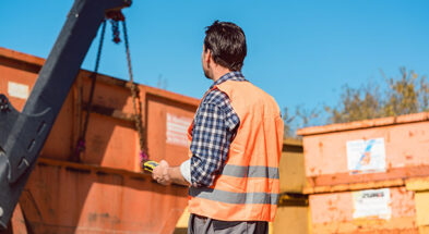 Abakus Nachlassverwertung - fachgerechte Entsorgung - Mann vor orangen Müllcontainern
